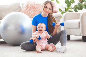 Young pretty mother working out with her little child at home