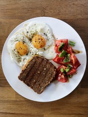 Frühstück oder Brunch mit Spiegeleiern, getoastetetem Sanchwich und Tomaten mit Basilikum
