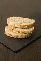Slices of homemade multigrain bread on black slate board