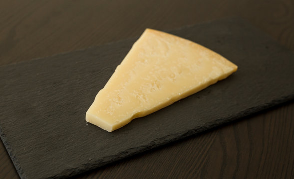 Slice of cheese on black slate board, close-up