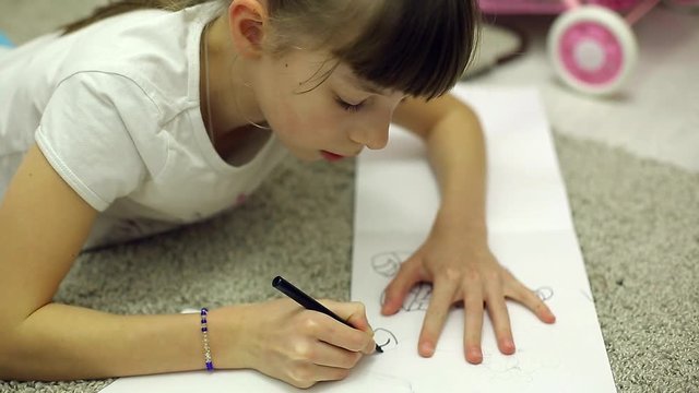 girls draw markers in the album lying on the floor in the room
