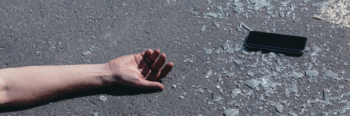 Panorama and close-up on victim's hand next to smartphone after traffic accident