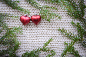 Warm picture with Christmas tree branches and hearts frame on knitted background