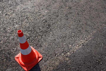 traffic cone, with white and orange stripes on gray asphalt, copy space
