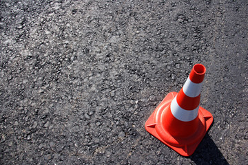 traffic cone, with white and orange stripes on gray asphalt, copy space