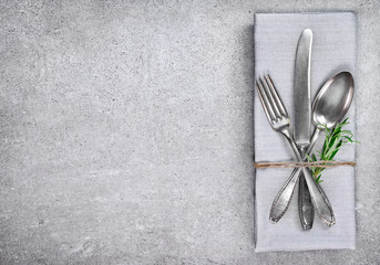 Table setting background with copy space. Concrete background with napkin, silverware and rosemary...