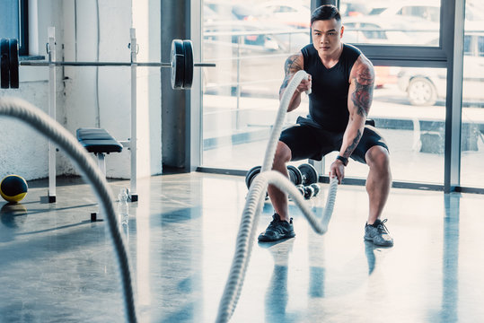 Young Asian Sportsman Working Out With Battle Ropes At Gym