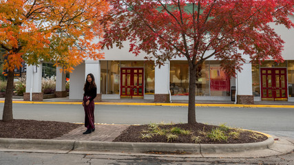 Thai woman standing under beautiful trees in front of shops in the fall