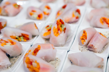 Vegetable spring rolls wrapped in rice paper cut in half in a sauce-pan with a spicy sauce. Catering concept vegetarians birthday, healthy nutrition
