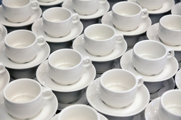 Lot of white porcelain tea pairs in piles in a straight line. Concept conference at the hotel, break, catering, breakfast