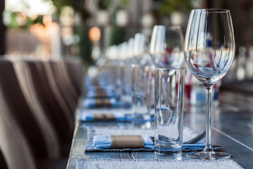 Restaurant serving and glass wine and water glasses, forks and knives on textile napkins stand in a row on a gray wooden table. Concept banquet, birthday, conference, group lunch