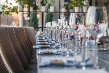 Restaurant serving and glass wine and water glasses, forks and knives on textile napkins stand in a row on a gray wooden table. Concept banquet, birthday, conference, group lunch