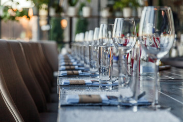 Restaurant serving and glass wine and water glasses, forks and knives on textile napkins stand in a row on a gray wooden table. Concept banquet, birthday, conference, group lunch