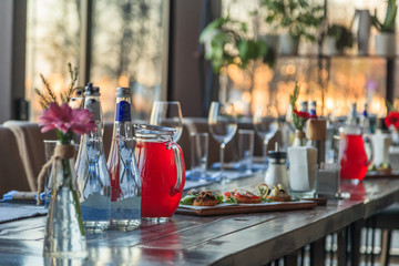 Restaurant serving, wine water glasses, appetizers, bruschetta, forks and knives on textile napkins stand in row on gray wooden table. Concept banquet, birthday, conference, group lunch