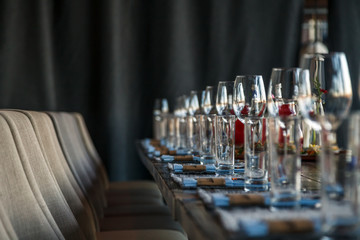 Restaurant serving and glass wine and water glasses, forks and knives on textile napkins stand in a row on a gray wooden table. Concept banquet, birthday, conference, group lunch