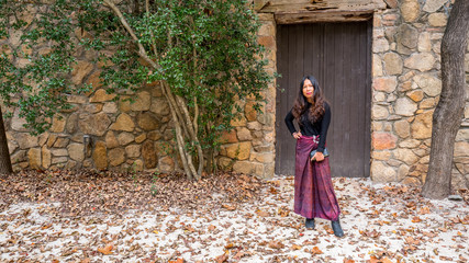 Woman in sarong standing on stage in stone amphitheater in front of brown door