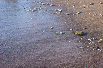 soft focus sea sand and stones shore line waterfront background texture and water waves in swash...