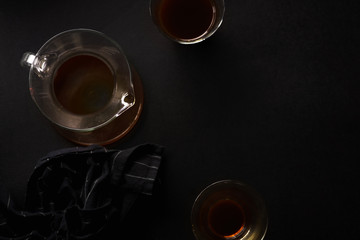 Pour over coffee in picther in two glasses on black background with black napkin. Overhead view