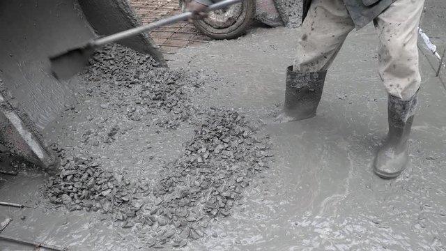 close up of construction workers pouring cement on a rural road
