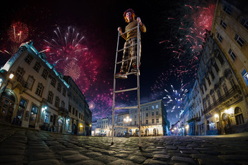 Night street circus performance whit clown balanced in ladder. Festival city background. fireworks...
