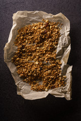 Top view of roasted granola with nuts, flakes and raisins on parchment paper. Close up texture