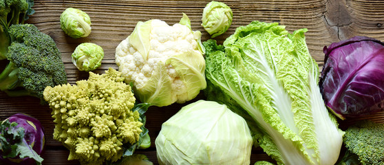 Different varieties of cabbages on wooden background. Organic fresh vegetables - cauliflower,...