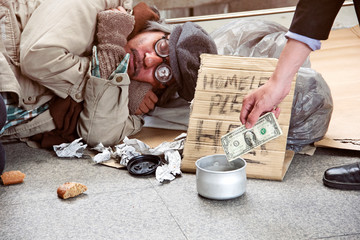 à¸ºBusiness man money donation to homeless man sleeping on walking street.