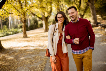 Young woman and man walking in city park holding hands