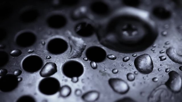 Close up on dripping water from faucet in a kitchen sink. Slow motion.