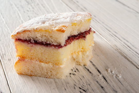 multi-layer sponge cake with bites on white wood background