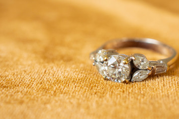 Jewelry diamond ring on golden fabric background close up