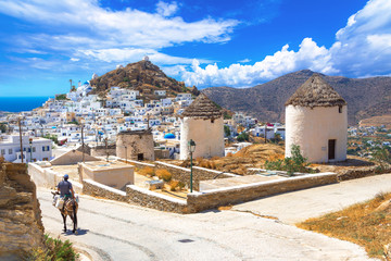 Traditional houses, wind mills, churches  and donkey in Ios island, Cyclades, Greece. - obrazy, fototapety, plakaty