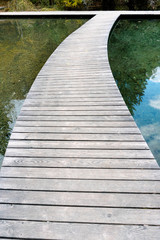 long curved wooden boardwalk and footpath over a blue mountain lake with reflections in the water