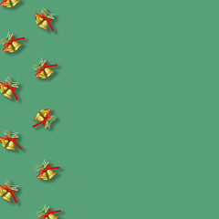 Two golden christmas bells with a red ribbon bow  on green background, New year greeting card.