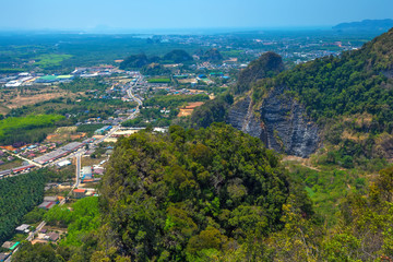 Fototapeta na wymiar Panoramic view from the top of the mountain to the neighborhood, green fields, forests, road, houses from a bird's flight. Tham Sua Thamsua Cave Temple Enlightenment Center, Krabi, Thailand.