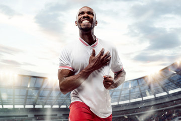 The football african player in motion on the field of stadium at day. The professional football,...