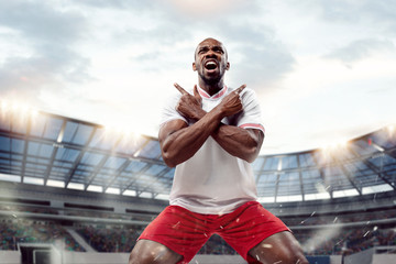 The football african player in motion on the field of stadium at day. The professional football,...