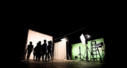 Low key silhouette lighting of VDO production behind the scenes which film crew team are setting up camera and set for shooting and waiting for movie director okay with the scenes in monitor.
