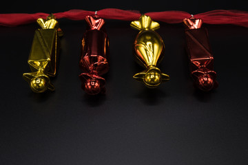 Red and golden christmas candy decorations on black background.