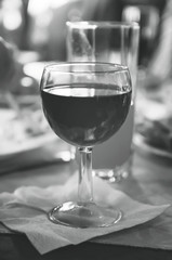 A glass of red wine is on the table. Black and white photography.