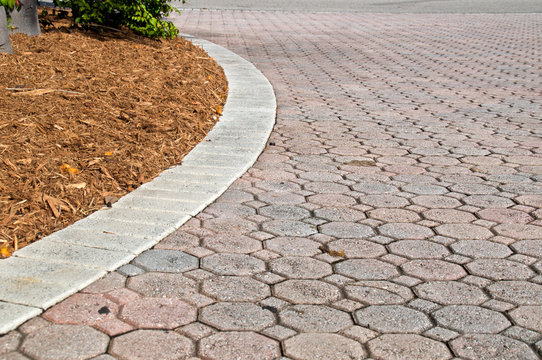 curved low angle brick paver driveway with mulch