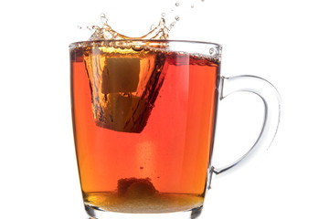 Dissolving a piece of sugar in tea in a transparent mug on a white background, a storm in a glass
