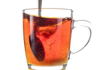 Dissolving a piece of sugar in tea in a transparent mug on a white background, a storm in a glass