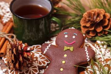 Christmas background. Tea in a metal green mug, traditional Christmas gingerbread, Christmas tree branches and cones on a wooden background close-up, top view