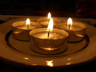 Obraz na płótnie Canvas Four small lighted Advent candels in dark