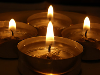 Four small lighted Advent candels in dark, close up