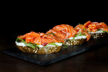 Sandwich with trout and herbs on black slate.