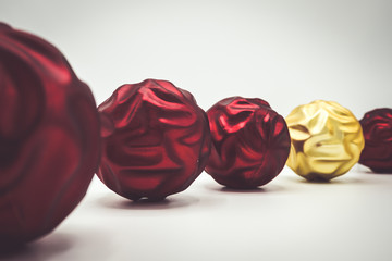 Desaturated wavy red and golden christmas balls on white.