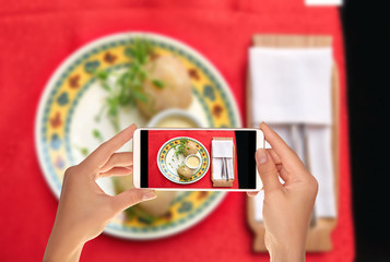 A tourist is taking a photo of traditional Lithuanian dishes from potatoes - zeppelins with sauce on a plate on a mobile phone © maksim_e