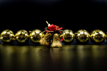 Golden Christmas balls and bells on black background.